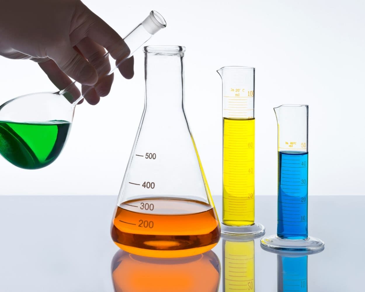 Laboratory glassware holding green, orange, yellow and blue liquids